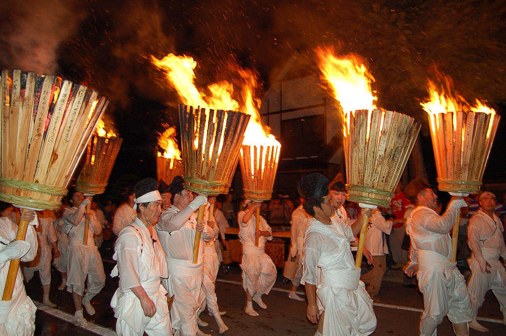那智・美瑛火祭で白装束の人々が燃え盛る大松明を担ぐ様子